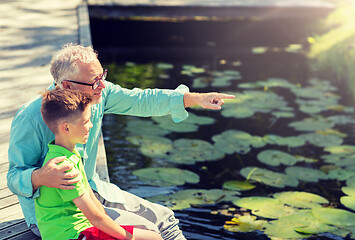 Image showing grandfather and grandson sitting on river berth