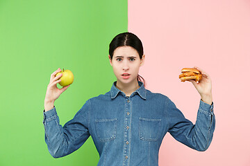 Image showing Diet. Dieting concept. Healthy Food. Beautiful Young Woman choosing between fruits and unhelathy fast food