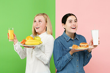 Image showing Diet. Dieting concept. Healthy Food. Beautiful Young Women choosing between fruits and unhelathy fast food