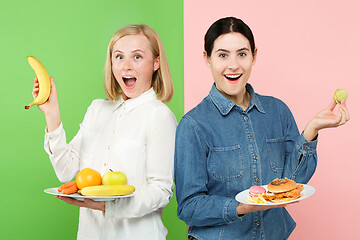 Image showing Diet. Dieting concept. Healthy Food. Beautiful Young Women choosing between fruits and unhelathy fast food