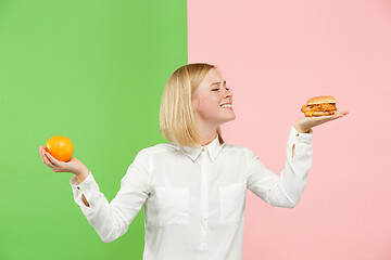 Image showing Diet. Dieting concept. Healthy Food. Beautiful Young Woman choosing between fruits and unhelathy fast food