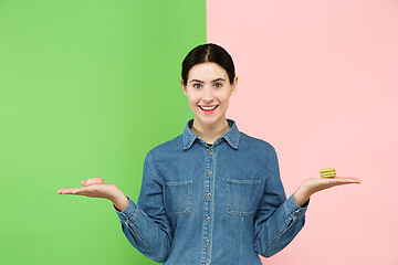 Image showing Young beautiful woman holding macaroons pastry in her hands