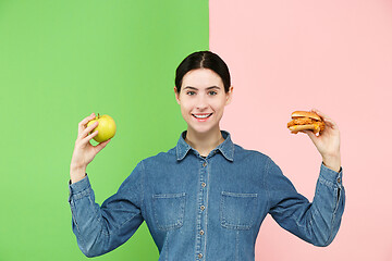 Image showing Diet. Dieting concept. Healthy Food. Beautiful Young Woman choosing between fruits and unhelathy fast food