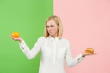 Image showing Diet. Dieting concept. Healthy Food. Beautiful Young Woman choosing between fruits and unhelathy fast food