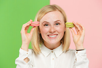 Image showing Young beautiful woman holding macaroons pastry in her hands