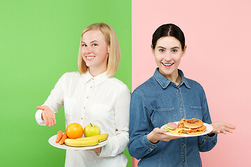 Image showing Diet. Dieting concept. Healthy Food. Beautiful Young Women choosing between fruits and unhelathy fast food