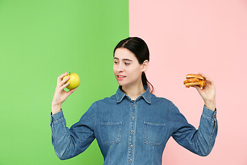 Image showing Diet. Dieting concept. Healthy Food. Beautiful Young Woman choosing between fruits and unhelathy fast food