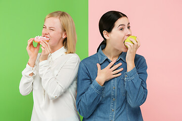 Image showing Diet. Dieting concept. Healthy Food. Beautiful Young Women choosing between fruits and unhelathy cake