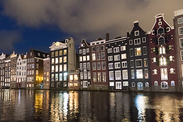 Image showing Beautiful tranquil scene of city of Amsterdam at dusk. Bicycles along the street and on the bridge over the canal.