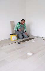 Image showing worker installing the ceramic wood effect tiles on the floor