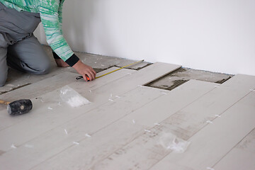 Image showing worker installing the ceramic wood effect tiles on the floor