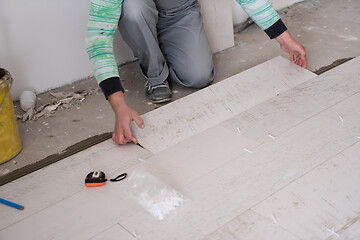 Image showing worker installing the ceramic wood effect tiles on the floor