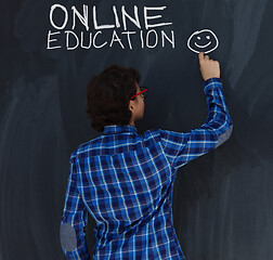 Image showing Teen Boy with chalk  writing on black chalkboard online educatio