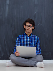 Image showing Arab teenager using laptop to work on homework  at home