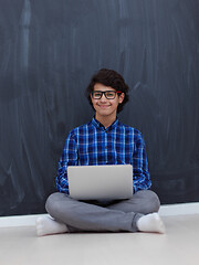 Image showing Arab teenager using laptop to work on homework  at home