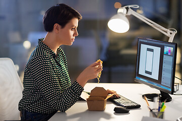 Image showing female designer eating and working at night office