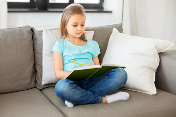 Image showing little girl with diary sitting on sofa at home