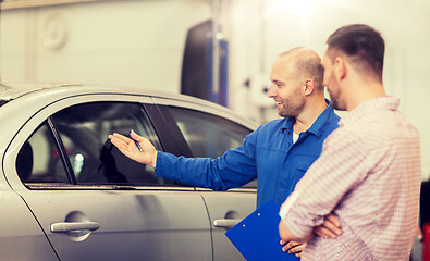 Image showing auto mechanic with clipboard and man at car shop