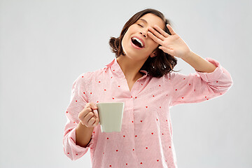 Image showing happy yawning young woman in pajama with coffee