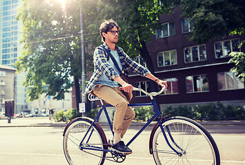 Image showing young hipster man with bag riding fixed gear bike