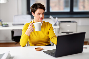 Image showing businesswoman with laptop drinks coffee at office