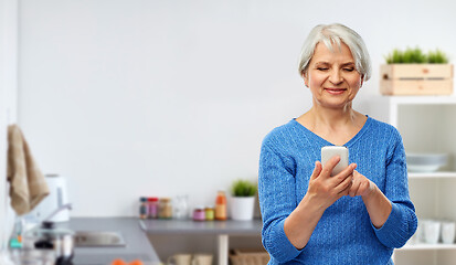 Image showing smiling senior woman using smartphone in kitchen