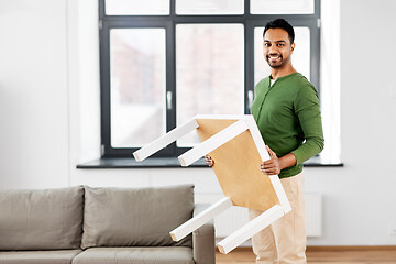 Image showing happy indian man holding coffee table at home