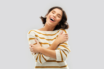 Image showing happy woman in striped pullover hugging herself