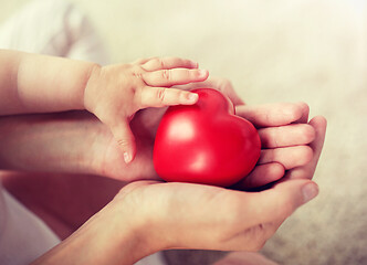 Image showing close up of baby and mother hands with red heart