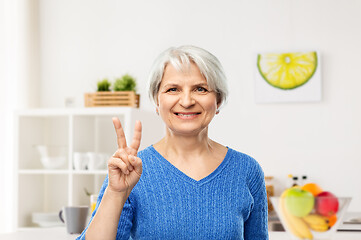 Image showing smiling senior woman showing peace in kitchen