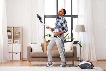 Image showing indian man with vacuum cleaner having fun at home