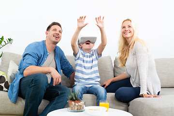 Image showing Happy family at home on living room sofa having fun playing games using virtual reality headset