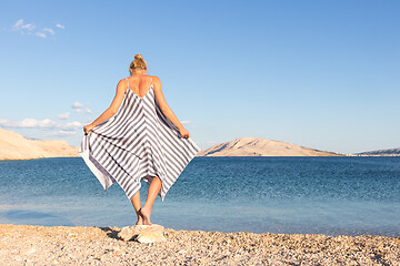 Image showing Happy carefree woman enjoying late afternoon walk on white pabbled beach on Pag island, Croatia