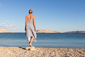 Image showing Happy carefree woman enjoying late afternoon walk on white pabbled beach on Pag island, Croatia