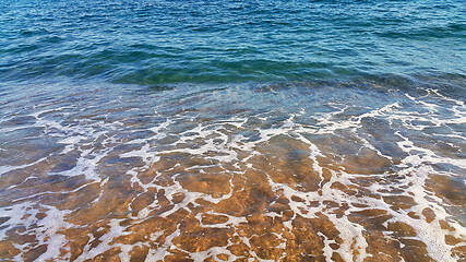 Image showing Clear sea water with white foam in the coastal sand