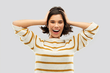 Image showing happy woman in pullover holding to her head