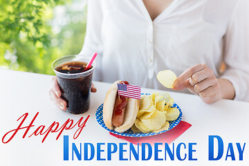 Image showing close up of woman eating chips, hot dog and cola