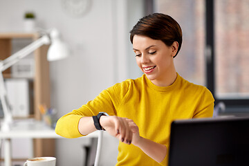 Image showing happy businesswoman using smart watch at office