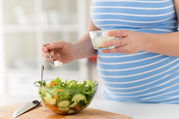 Image showing close up of pregnant woman cooking salad at home