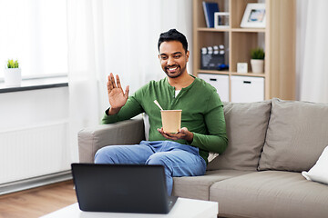 Image showing man having video call on laptop and eating at home