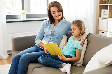 Image showing happy girl with mother reading book at home