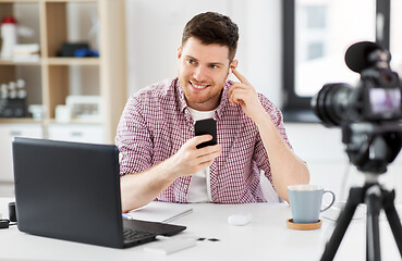 Image showing male blogger with earphones videoblogging at home