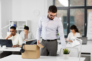 Image showing sad fired male office worker with personal stuff