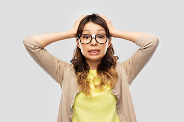 Image showing asian female student in glasses holding to head