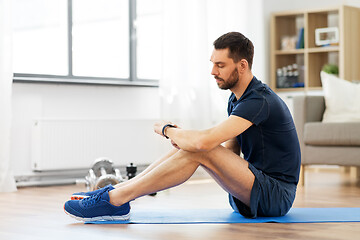 Image showing man with fitness tracker exercising at home