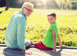 Image showing grandfather and grandson sitting on river berth