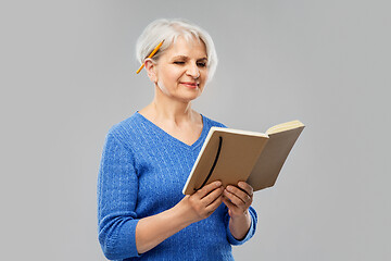 Image showing senior woman with pencil and diary or notebook