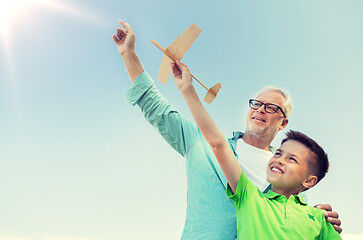 Image showing senior man and boy with toy airplane over sky