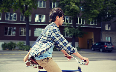 Image showing young hipster man with bag riding fixed gear bike