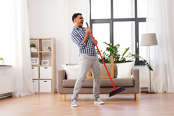 Image showing man with broom cleaning and singing at home